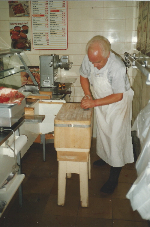 Josef Bank beim Abkratzen des Hackstocks im Laden um 1991